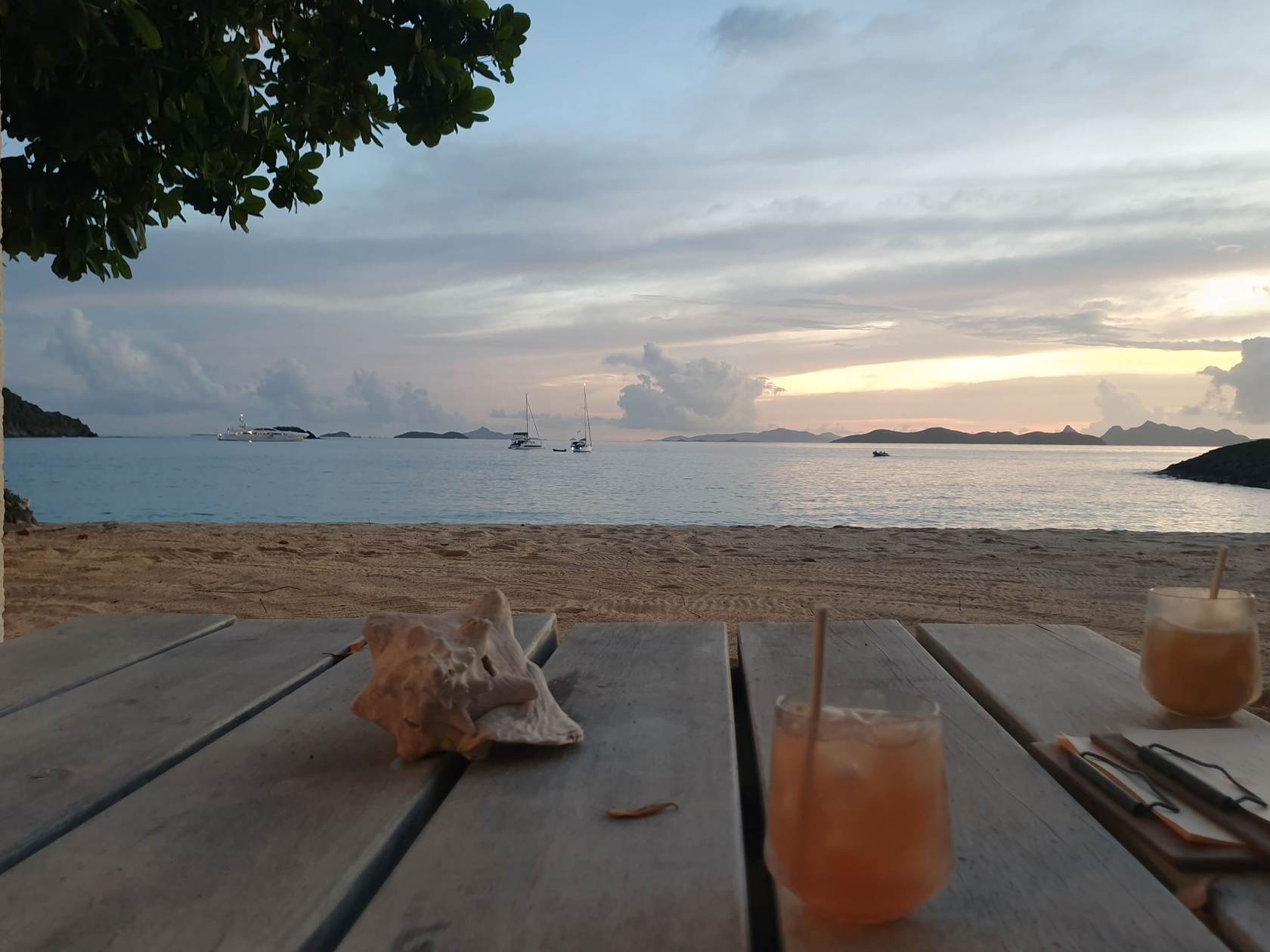 Fruchtige Cocktails auf einem Holztisch am Strand bei Sonnenuntergang.