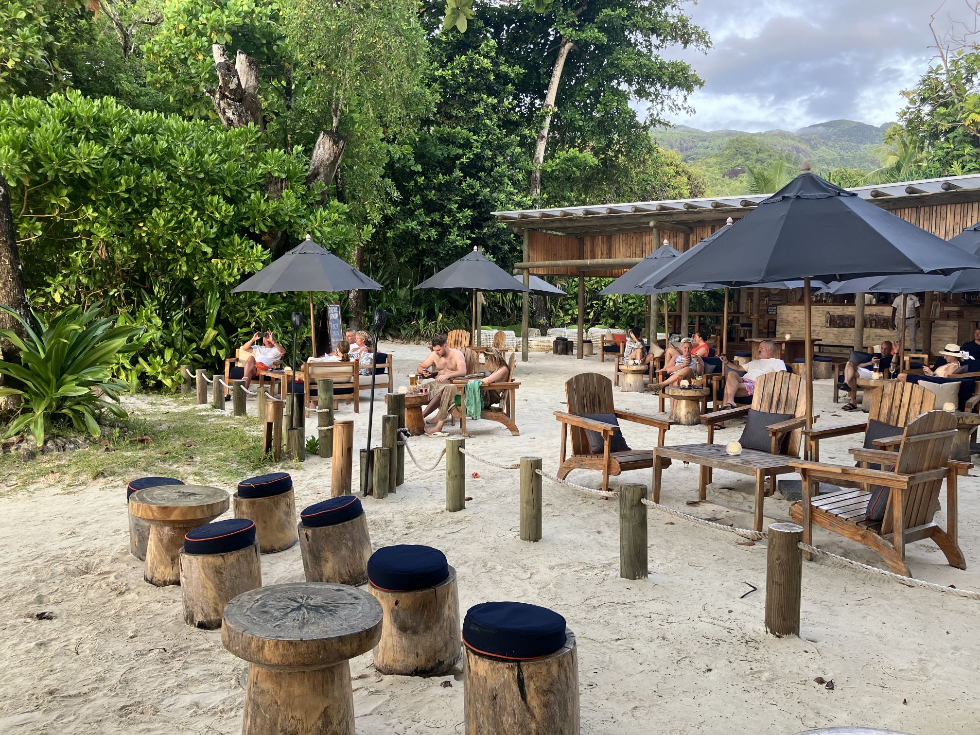Strandbar mit Holzhockern, Holztischen und Sonnenschirmen am Strand von Port Launay (Seychellen)