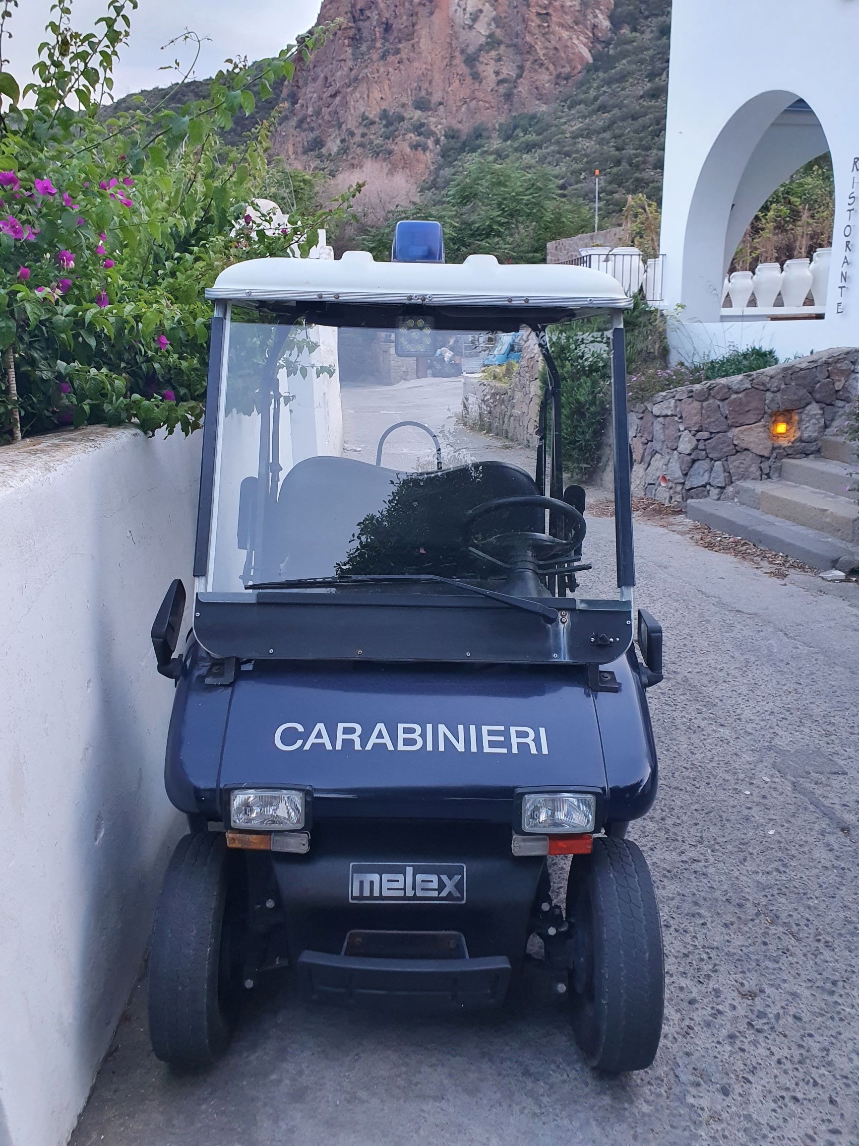 Golfcart mit der Aufschrift Carabinieri an einer weißen Mauer in mediterranem Dorf