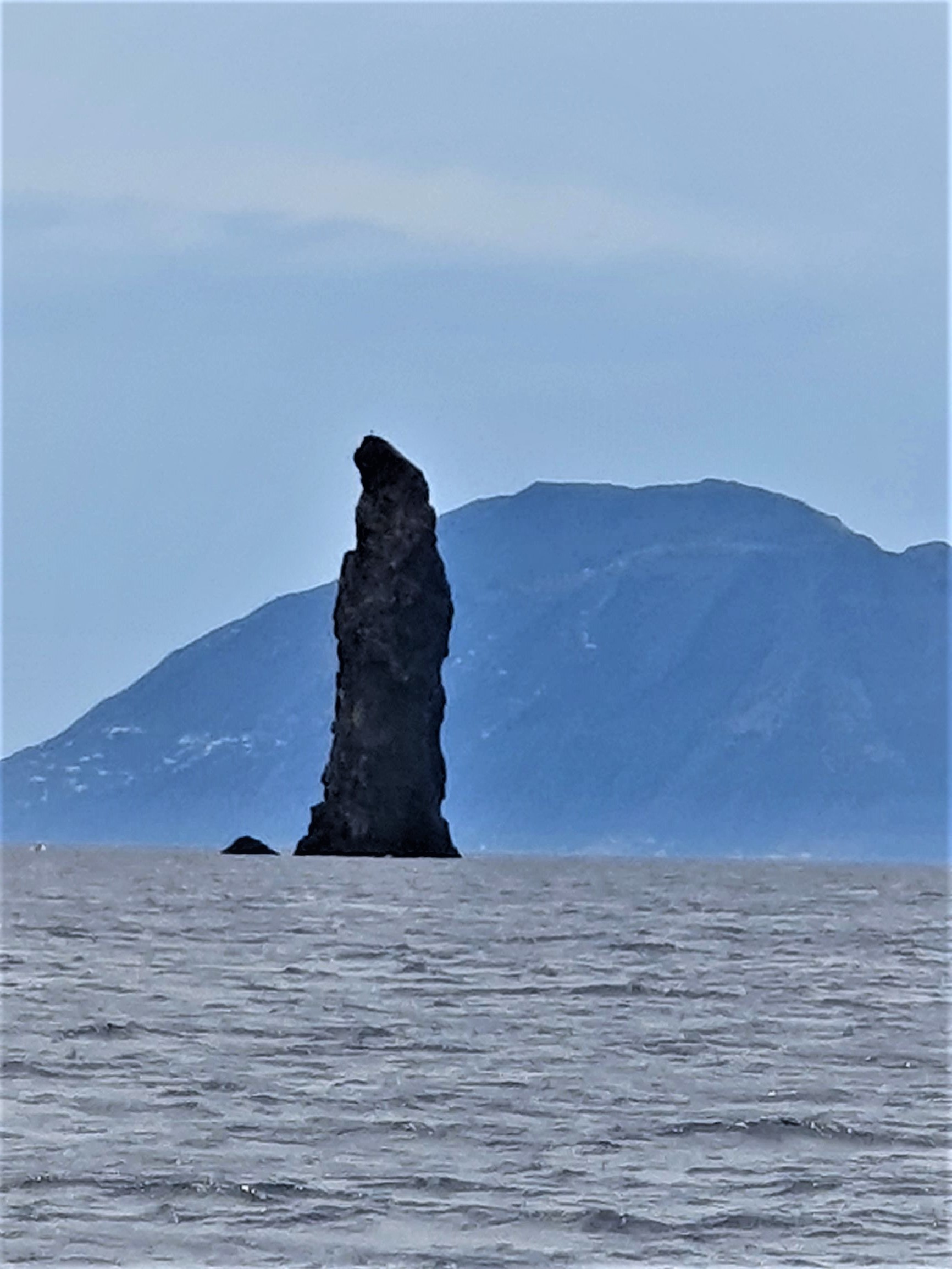 Felsen aus Vulkangestein ragt aus dem Wasser.